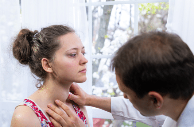 Doctor inspecting young woman with enlarged thyroid gland goiter