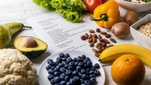 Fruits surrounding list of food nutrition plan as part of lipidologist cholesterol treatment