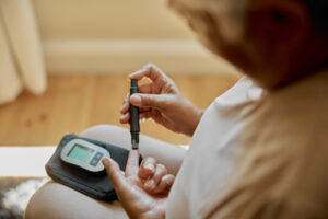 Woman checking blood sugar with a glucose meter at home.